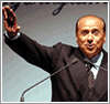 [Silvio Berlusconi, con un ghigno strano e la mano destra alzata]